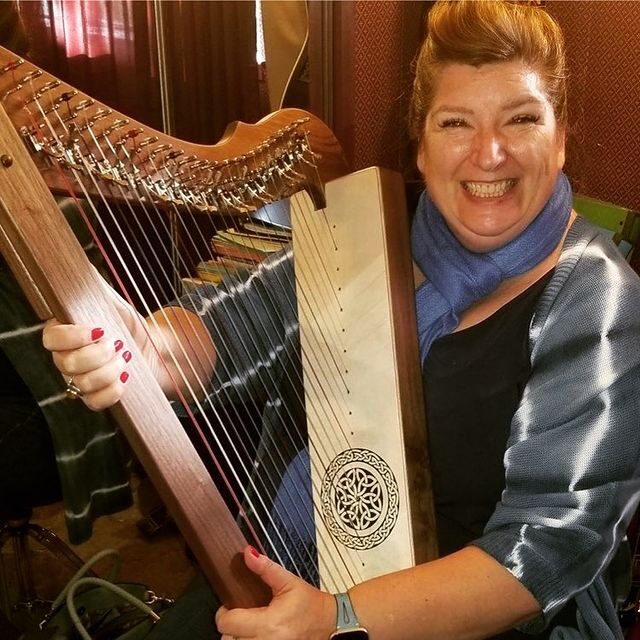 Smiling woman holding harp 