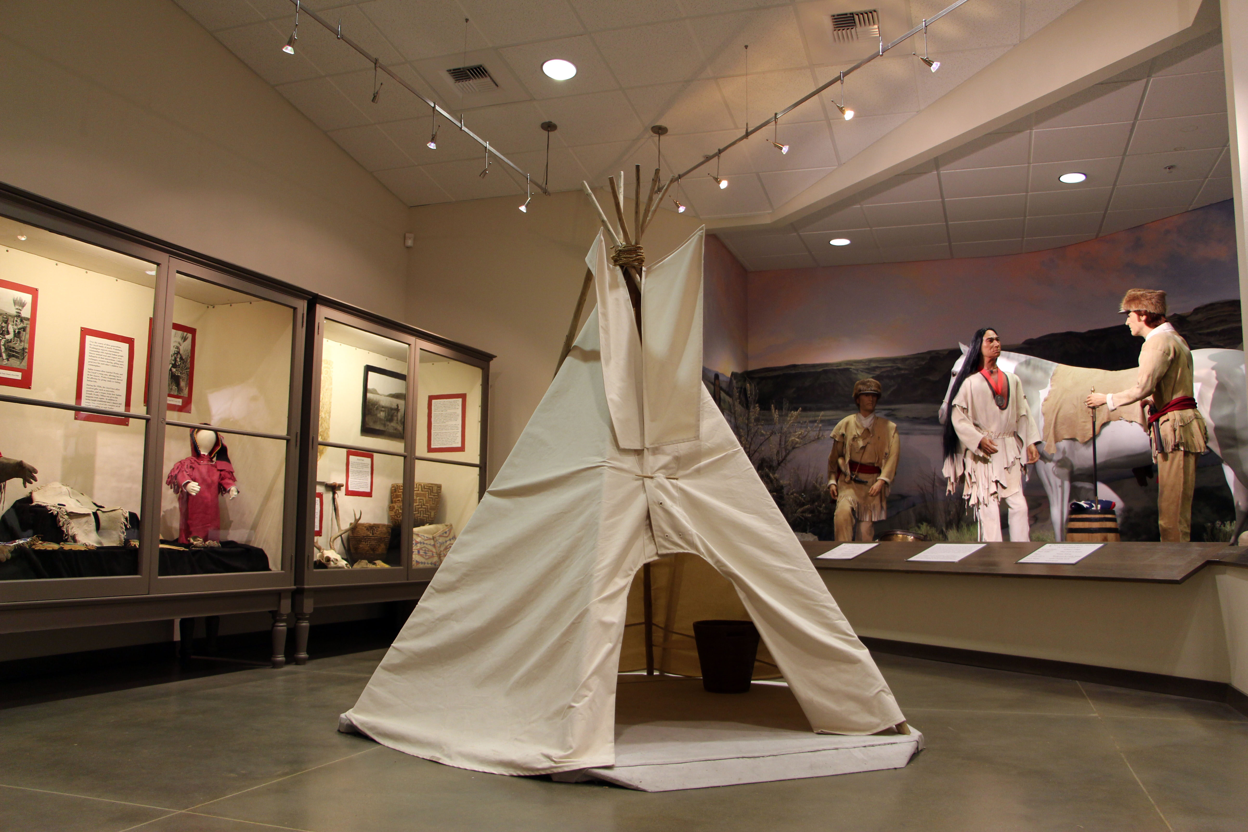 The interior of a museum gallery with a play tepee and two exhibits in the background