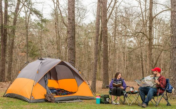 couple reading next to tent at campsite