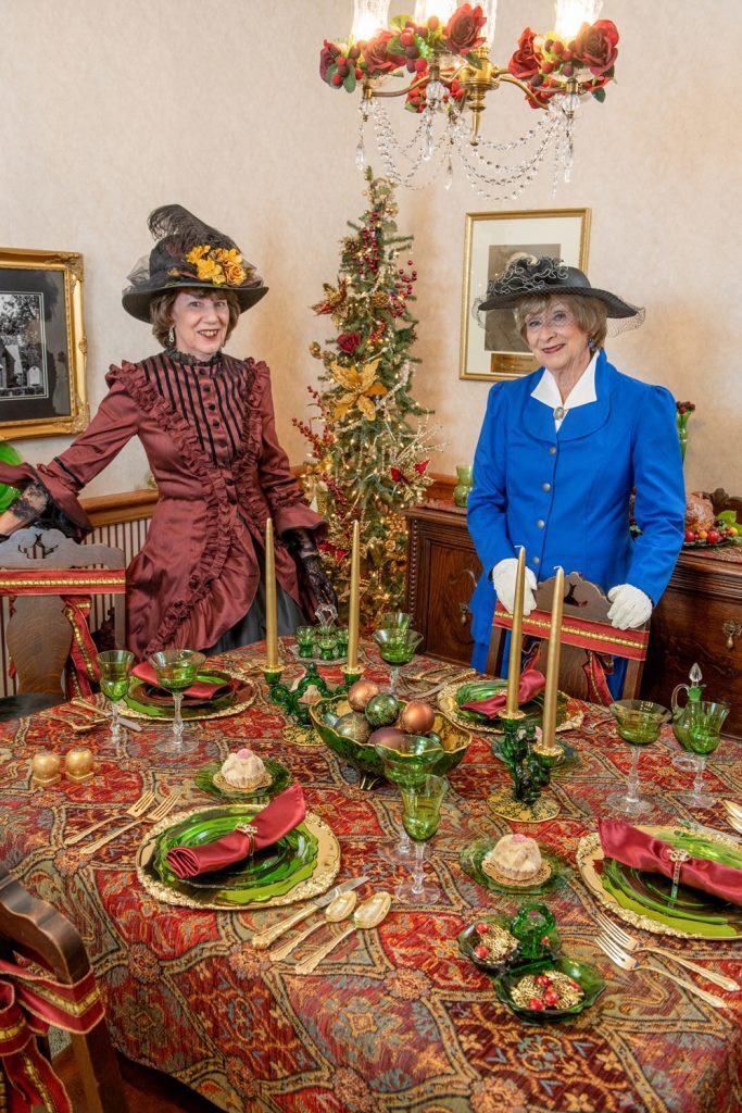 Women dressed in historic clothes at table set with Cambridge glassware